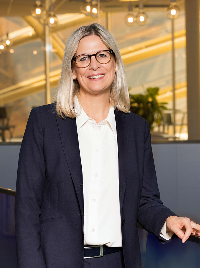 stefanie-schmitz Stefanie Schmitz in suit, wearing glasses, smiling.